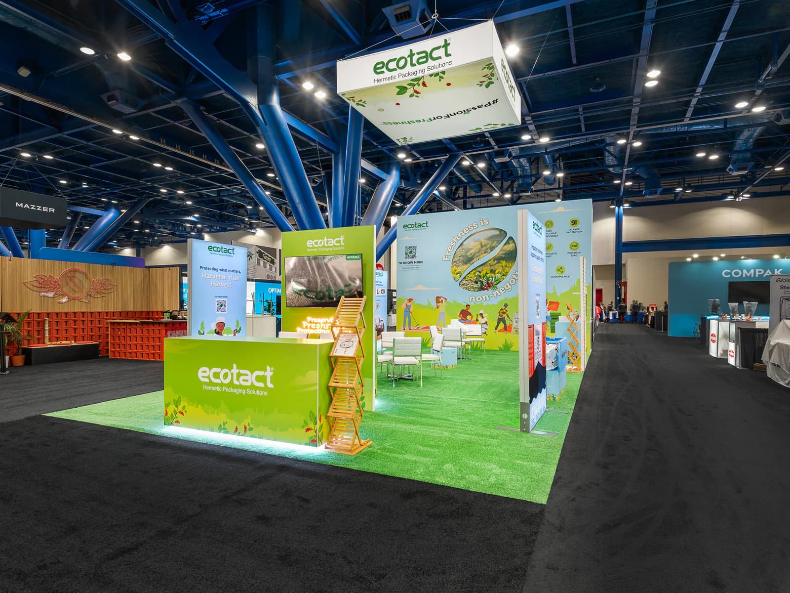 Bright green island exhibit with product displays and suspended cube signage.