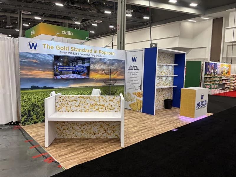 Wood-look corner exhibit with open shelving, product displays, and a landscape mural.
